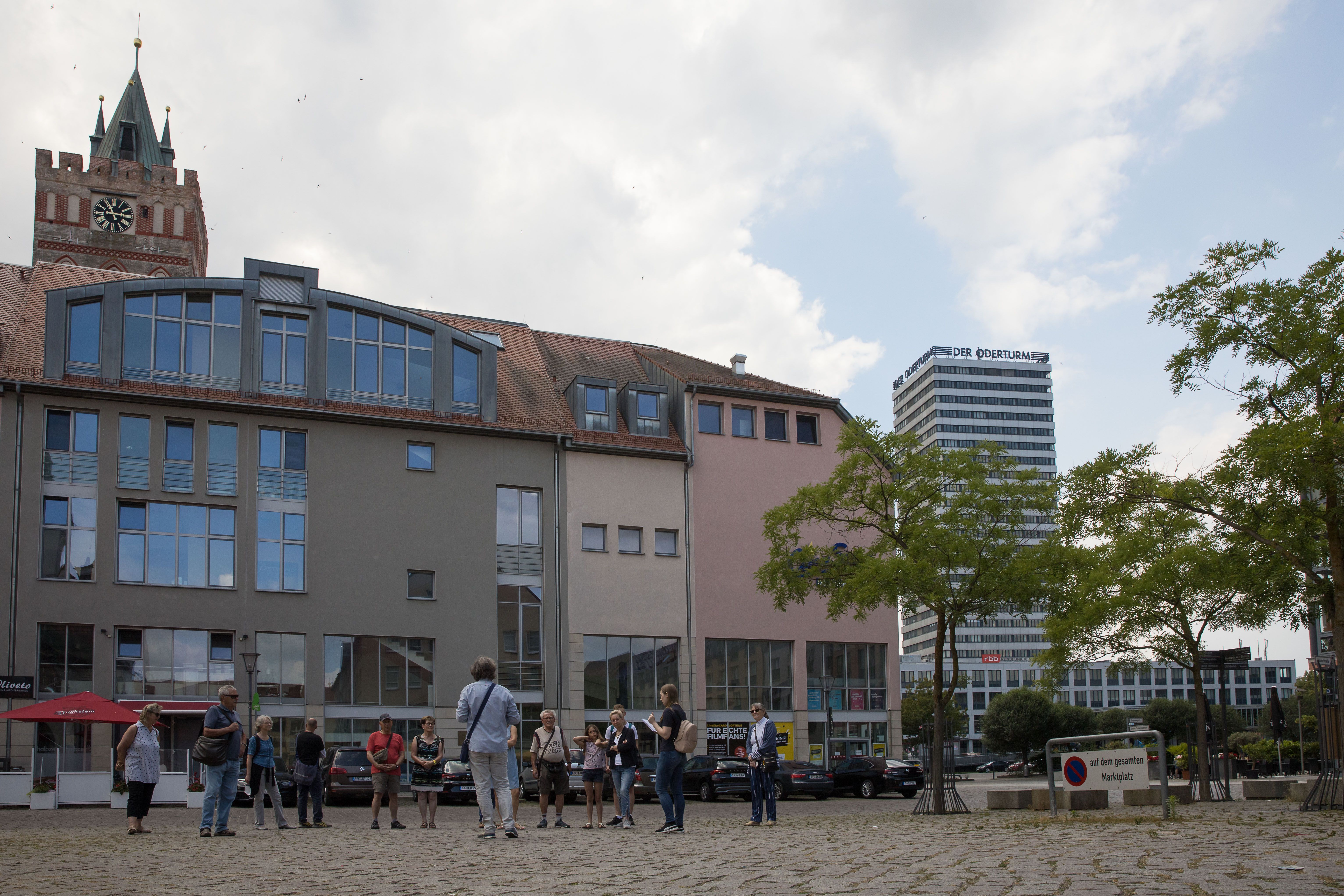 Eine Gruppe von Menschen mit dem Gästeführer steht auf dem Markplatz, im Hintergrund Oderturm zu sehen