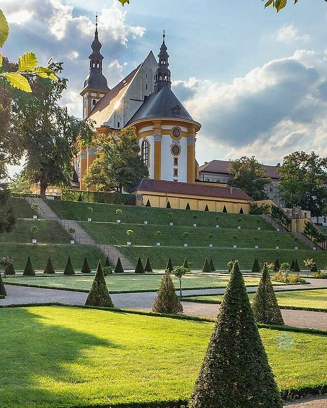 Ein  Klostergarten mit der Kirche am Berg